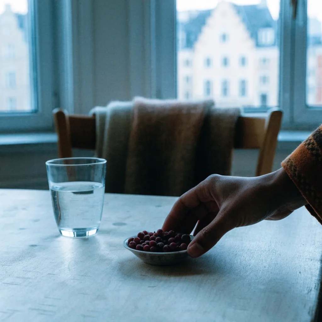A woman writing a message at a birch kitchen table with a mug of tea beside her